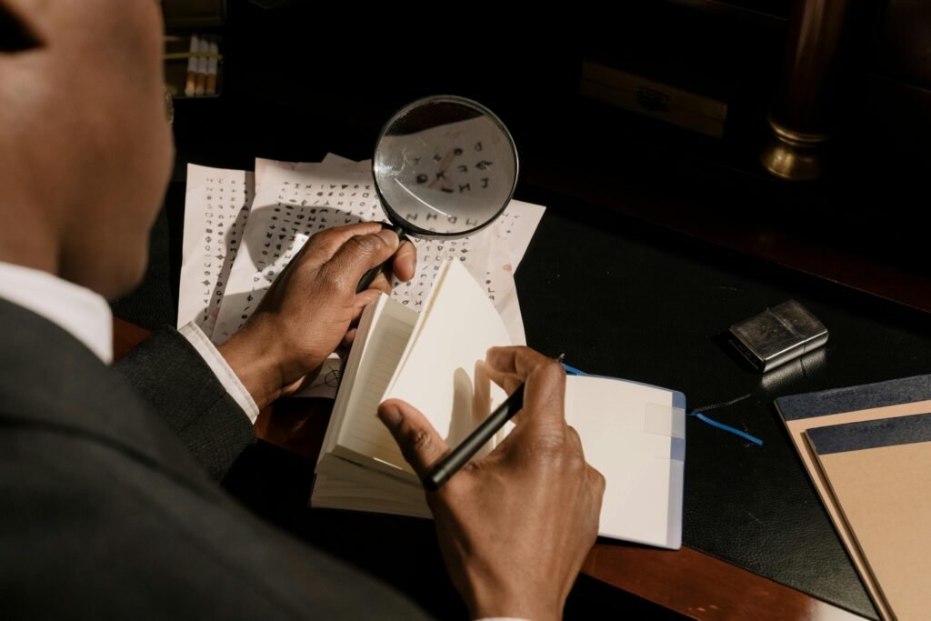 Close-up of a man examining documents with a magnifying glass while taking notes, symbolizing legal investigation, evidence review, and case preparation in criminal defence in Toronto.