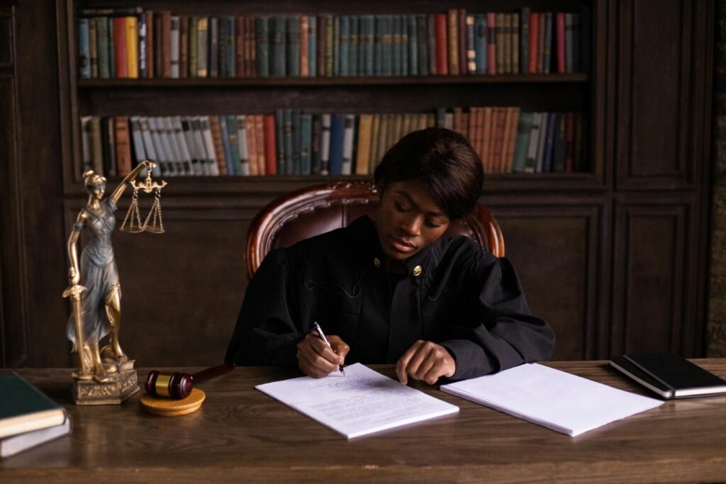 A judge in a courtroom signing legal documents at a desk with law books, a gavel, and Lady Justice statue — symbolizing the legal system and the costs of criminal defence in Toronto.