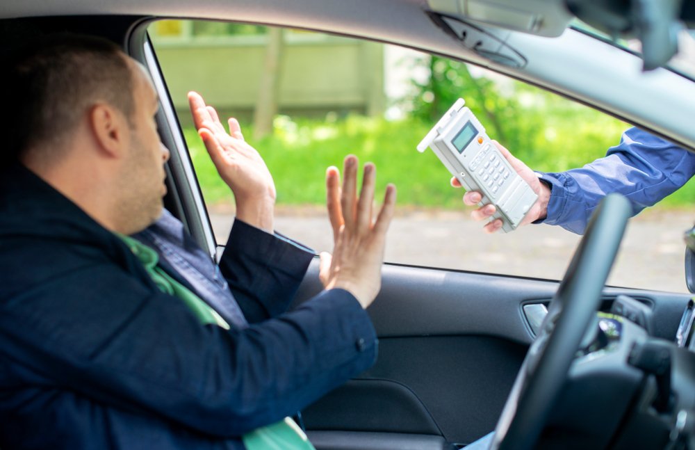 Driver raising hands in refusal as a police officer presents a breathalyzer during a roadside stop, illustrating penalties for refusing a test under Ontario alcohol limit for driving laws.